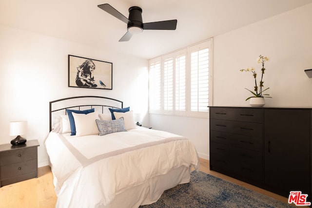 bedroom featuring ceiling fan, multiple windows, and wood-type flooring