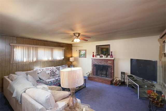 living room with ceiling fan, a brick fireplace, wood walls, and dark colored carpet