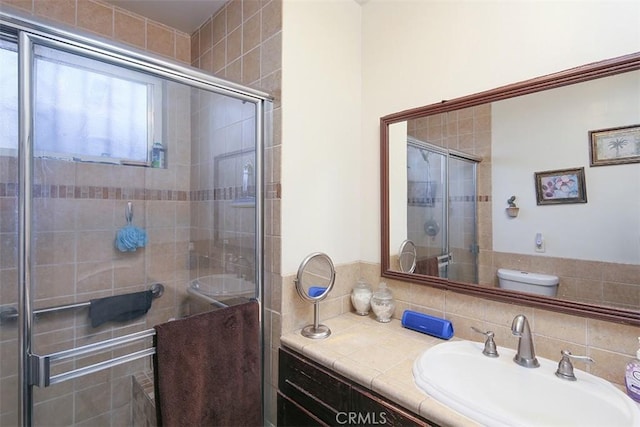 bathroom featuring a shower with shower door, toilet, and vanity