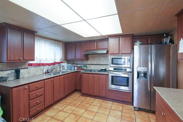 kitchen with appliances with stainless steel finishes, decorative backsplash, a drop ceiling, and sink