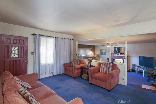 living room with ceiling fan, a fireplace, and dark carpet