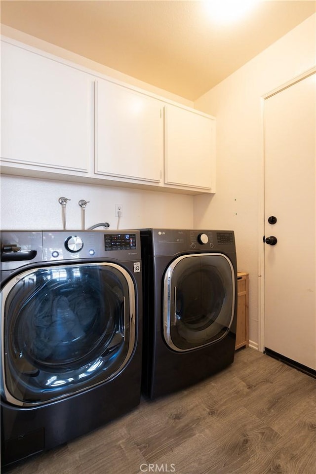 laundry room featuring cabinets, washer and clothes dryer, and dark hardwood / wood-style flooring