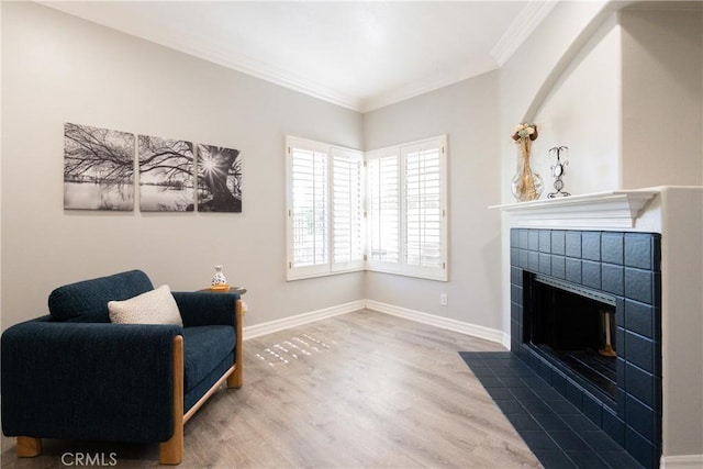 living area with hardwood / wood-style floors, crown molding, and a tiled fireplace