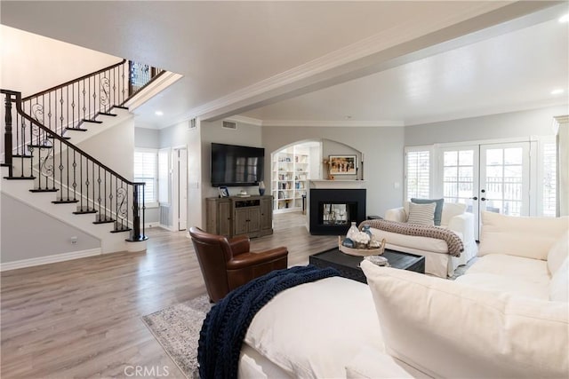 living room with french doors, ornamental molding, a multi sided fireplace, and hardwood / wood-style flooring