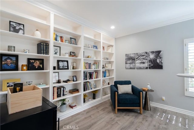 living area with hardwood / wood-style floors and ornamental molding