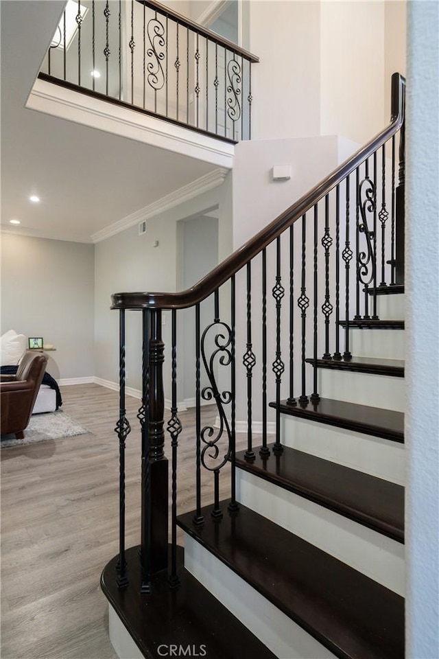 staircase featuring ornamental molding and hardwood / wood-style floors