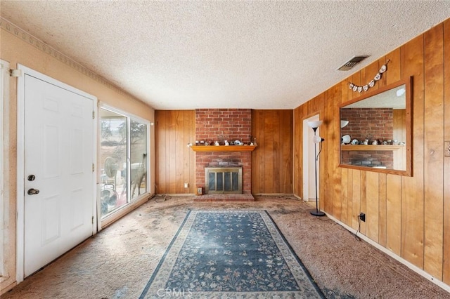 unfurnished living room featuring a textured ceiling, a fireplace, and wood walls