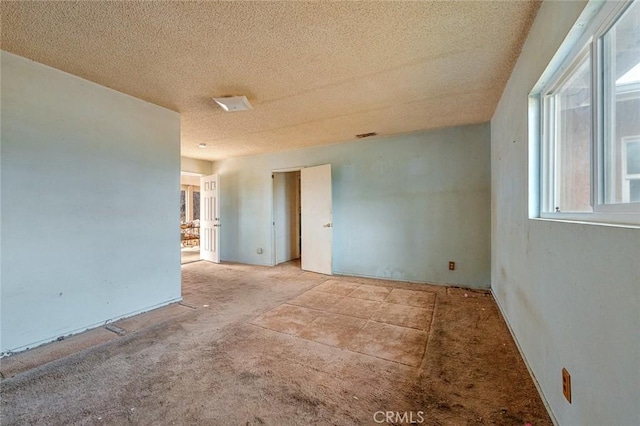 unfurnished room with a textured ceiling