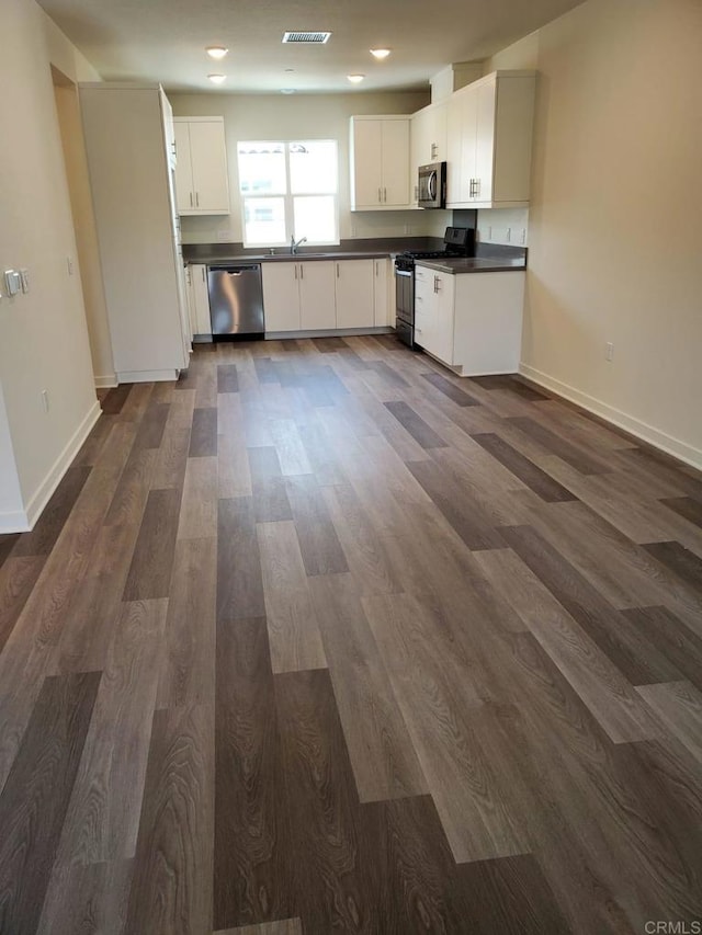 kitchen with white cabinetry, appliances with stainless steel finishes, and dark hardwood / wood-style flooring