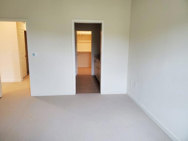 unfurnished bedroom featuring a spacious closet, a closet, and carpet flooring