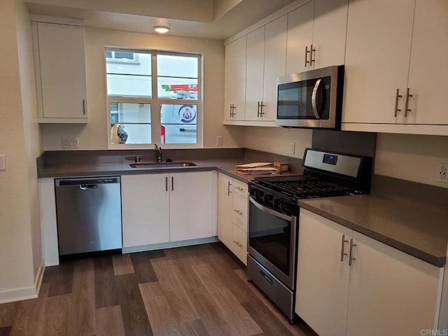 kitchen featuring dark wood-type flooring, white cabinets, appliances with stainless steel finishes, and sink