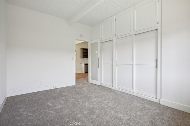 unfurnished bedroom with light colored carpet, a closet, and beamed ceiling