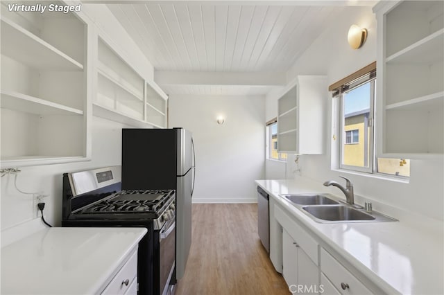 kitchen with beamed ceiling, appliances with stainless steel finishes, white cabinets, and sink