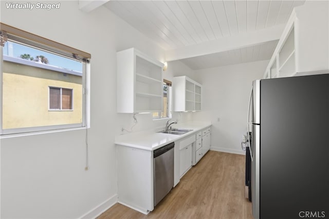 kitchen with white cabinets, stainless steel appliances, plenty of natural light, light hardwood / wood-style flooring, and beam ceiling