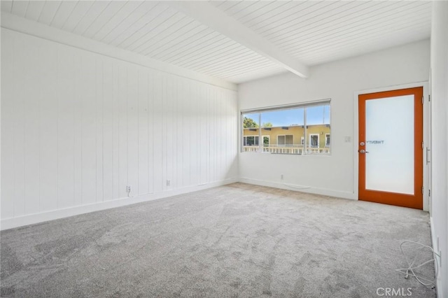 spare room with carpet and beamed ceiling