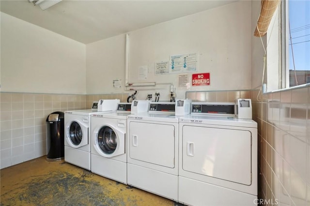 laundry room featuring tile walls and washing machine and clothes dryer