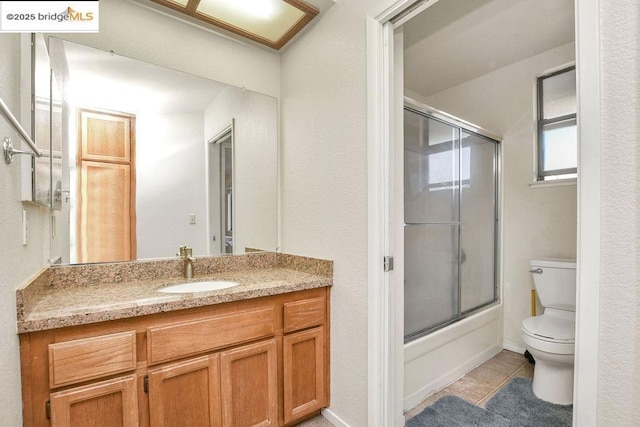 full bathroom with toilet, bath / shower combo with glass door, tile patterned flooring, and vanity