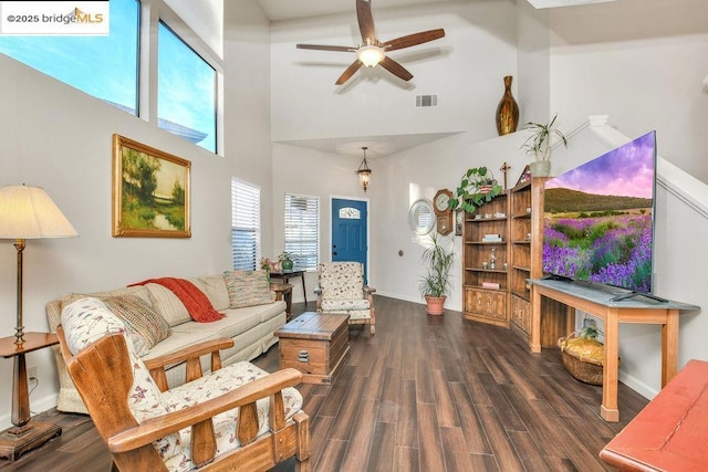 living room featuring dark wood-type flooring, a high ceiling, and ceiling fan