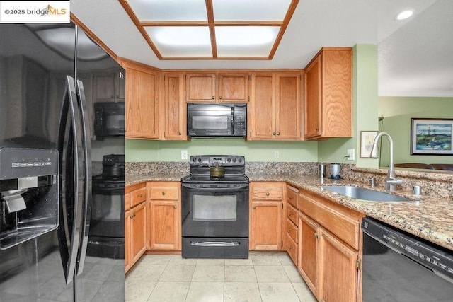 kitchen featuring black appliances, light stone countertops, sink, and light tile patterned flooring