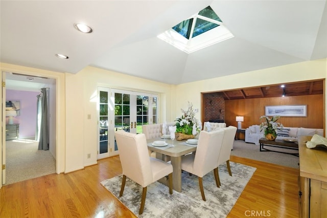 dining space featuring light hardwood / wood-style flooring, french doors, and vaulted ceiling with skylight