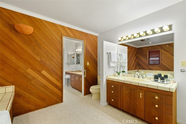 bathroom with vanity, crown molding, toilet, and wood walls