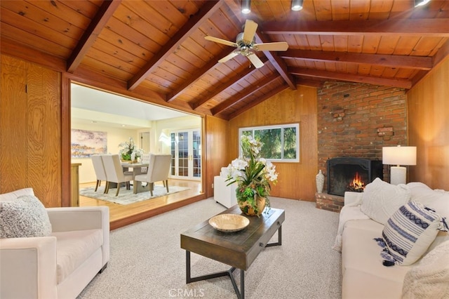 living room with vaulted ceiling with beams, a fireplace, light carpet, and wood walls