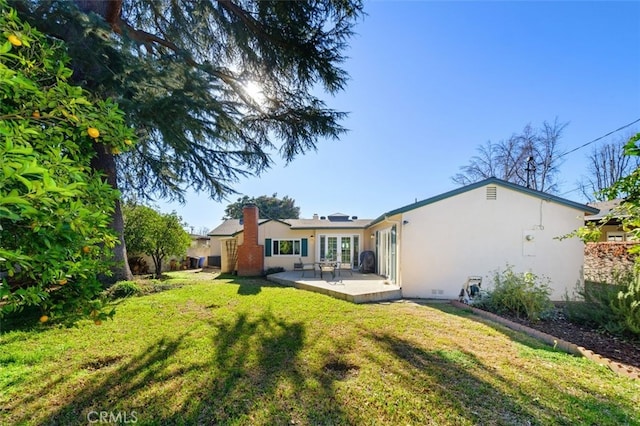 rear view of property with a patio and a lawn