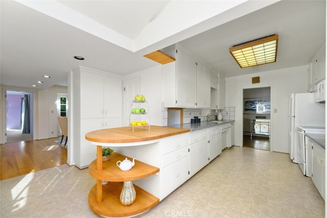 kitchen featuring decorative backsplash, white appliances, kitchen peninsula, and white cabinets