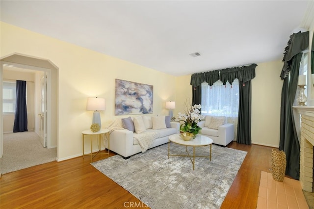 living room with hardwood / wood-style floors and a brick fireplace