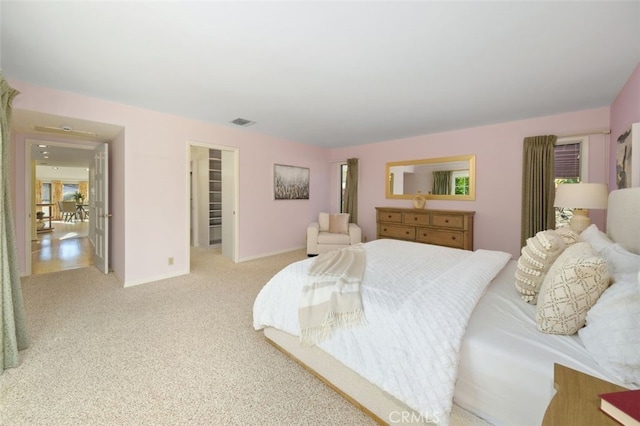 bedroom featuring a walk in closet and light carpet