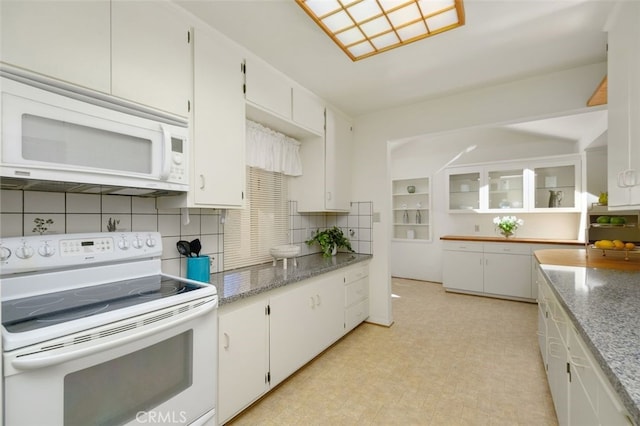 kitchen featuring white appliances, light stone countertops, decorative backsplash, and white cabinets