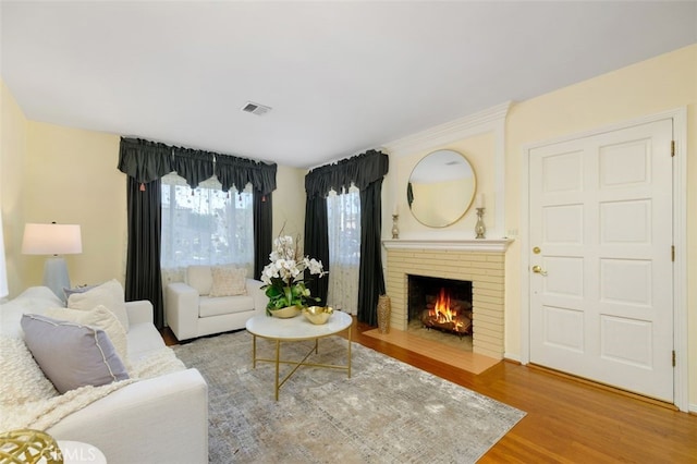 living room with wood-type flooring and a brick fireplace