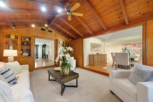 carpeted living room featuring vaulted ceiling with beams, wooden ceiling, ceiling fan, and wood walls