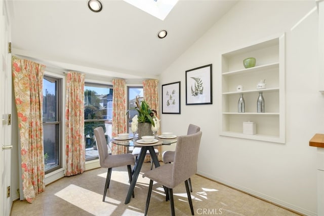 dining room with vaulted ceiling with skylight and built in features