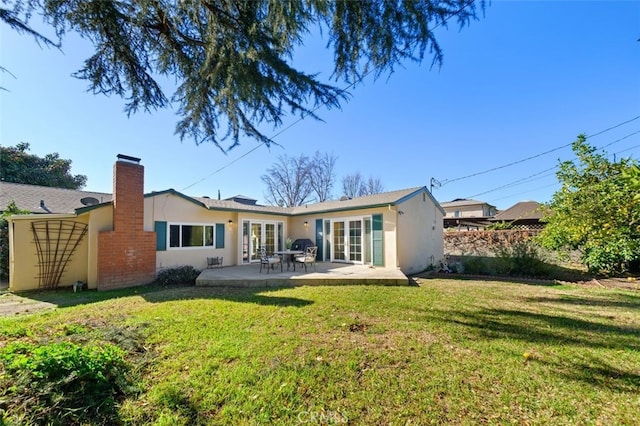 rear view of property featuring french doors, a yard, and a patio area