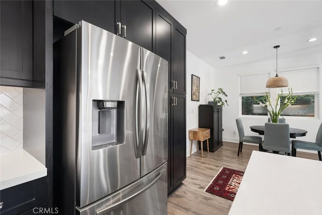 kitchen with tasteful backsplash, light hardwood / wood-style flooring, stainless steel fridge with ice dispenser, and pendant lighting