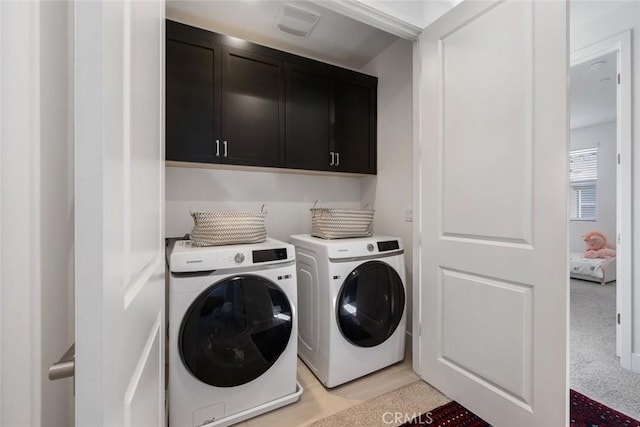 laundry room with light colored carpet, separate washer and dryer, and cabinets