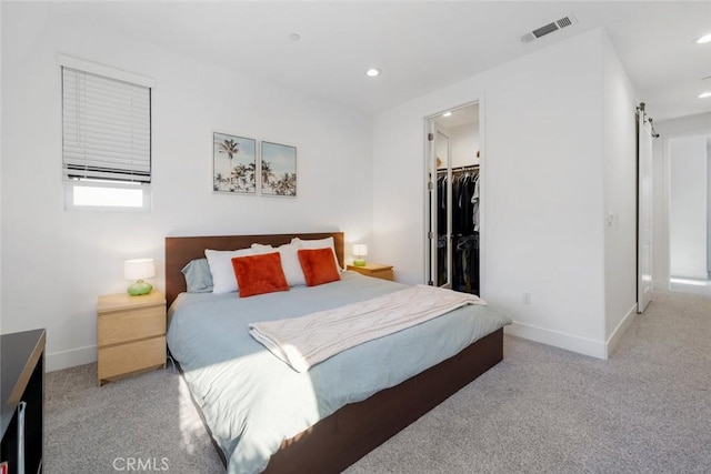 bedroom with light carpet, a closet, and a walk in closet