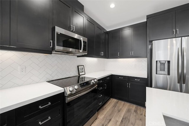 kitchen with light hardwood / wood-style floors, decorative backsplash, and stainless steel appliances