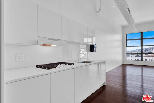 kitchen featuring dark hardwood / wood-style floors, white cabinetry, white gas cooktop, and sink