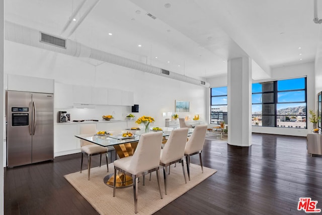 dining room with dark hardwood / wood-style flooring and a towering ceiling