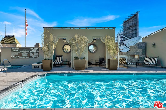 view of pool with a patio and exterior fireplace