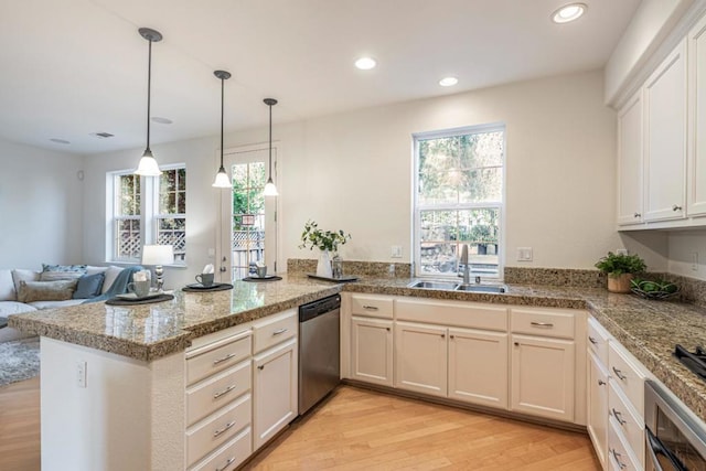 kitchen featuring sink, hanging light fixtures, stainless steel appliances, light hardwood / wood-style floors, and kitchen peninsula