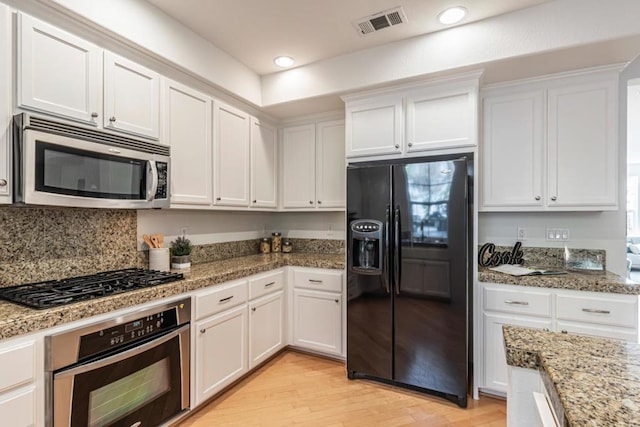 kitchen featuring light stone countertops, stainless steel appliances, and white cabinets