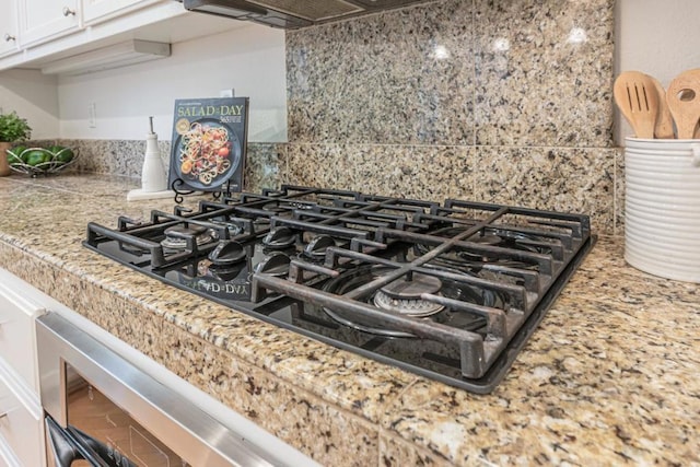 room details with backsplash, black gas stovetop, and exhaust hood