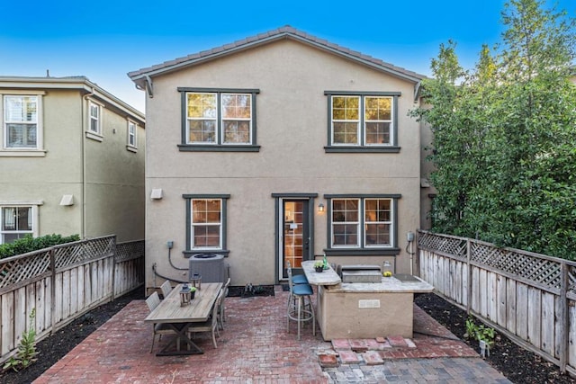 rear view of house with exterior kitchen, a patio, and cooling unit