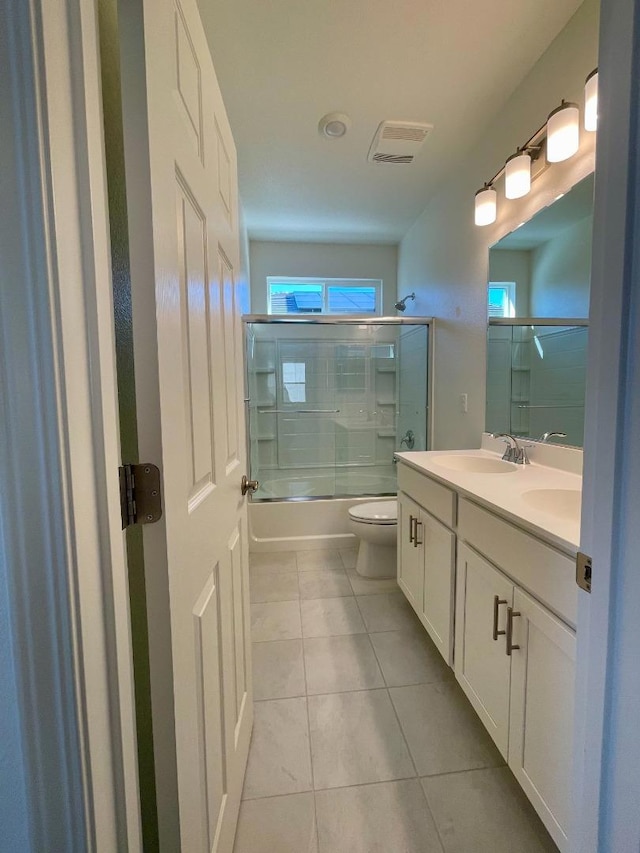 full bathroom with toilet, vanity, combined bath / shower with glass door, and tile patterned flooring