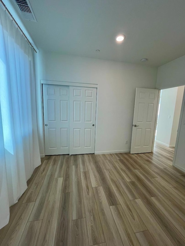 unfurnished bedroom featuring light wood-type flooring and a closet