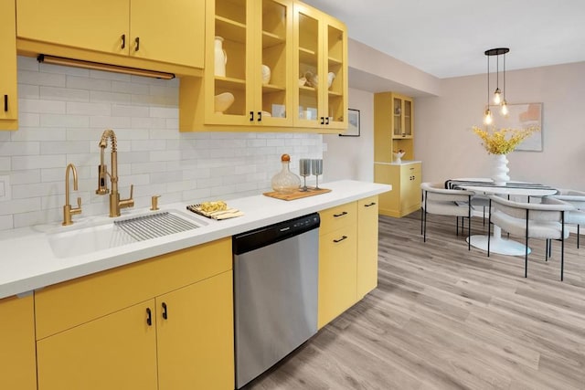 kitchen featuring pendant lighting, dishwasher, sink, backsplash, and light wood-type flooring