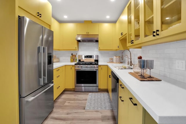 kitchen featuring sink, backsplash, light hardwood / wood-style floors, and appliances with stainless steel finishes